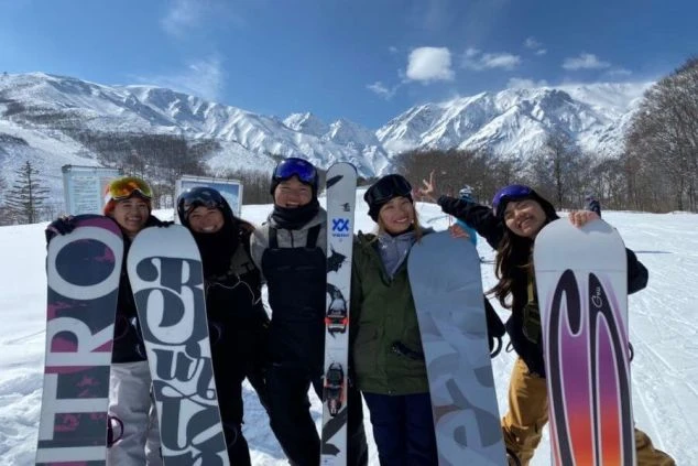 スキー場で、リゾートバイトの仲間たちと記念撮影。雄大な山々をバックに、最高の笑顔でポーズを決めています。