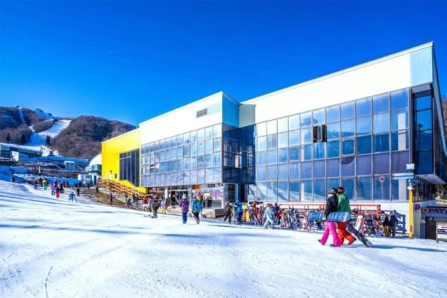 晴れた日のスキー場にある、近代的な建物の画像。多くの人が行き交い、活気がある。