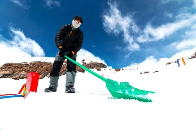 雪かき用の大きなシャベルを持っている男性の画像。