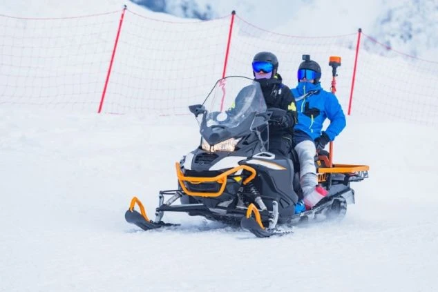 スノーモービルに乗っている二人の男性の画像。スキー場のパトロールや業務を連想させる。