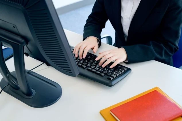 PCに向かって仕事をしている女性の画像。事務仕事のイメージ。
