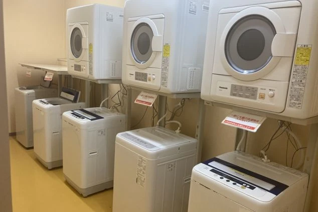 リゾートバイトの寮にある、清潔な共用ランドリー。洗濯機と乾燥機が複数台完備されており、いつでも洗濯が可能です。