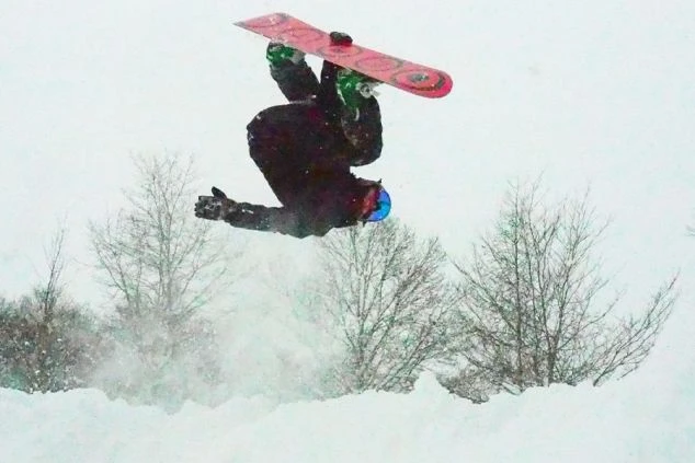 雪が降る中、バックフリップのような大技に挑戦するスノーボーダー。リゾートバイトで腕を磨けば、こんな上級者向けの技もできるようになるかもしれません。