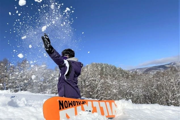 晴れ渡る青空の下、スノーボードを楽しむ様子。リフト券無料で、仕事の合間や休日にスキーやスノボを思いっきり満喫できます。
