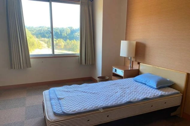 リゾートバイトの寮にある個室。窓から自然が見える明るい部屋で、ベッドや照明が備え付けられ、快適な一人暮らしが可能。