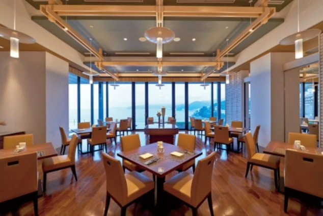 ホテルのダイニングの画像。大きな窓からは海が一望でき、温かみのある木目調のテーブルと椅子が並んでいる。リゾートバイトの仕事内容を表す、ホテルのダイニングの画像。
