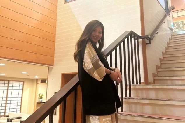 旅館のロビーの階段で、笑顔でポーズをとっている女性の画像。リゾートバイトの仕事内容を表す、ホテルや旅館のスタッフの画像。