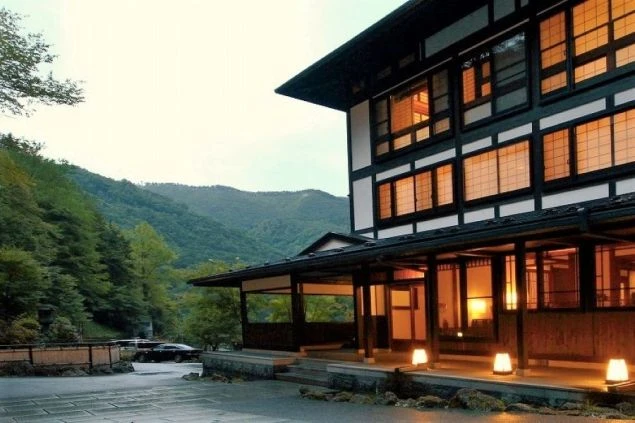 リゾートバイトの客室の画像。窓の外には緑豊かな庭園が広がり、部屋には座卓が置かれている。リゾートバイトの寮やホテルの客室の画像。