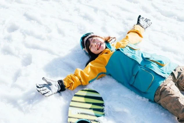 満面の笑みで雪の上に寝転ぶ女性。リゾートバイトの休日は、ゲレンデで思いっきり遊び、最高の思い出を作れます。