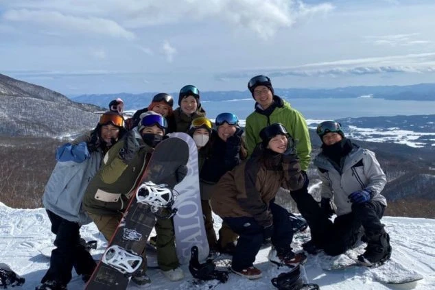 雪山を背景に笑顔でポーズをとる仲間たち。リフト券や食事代無料など、たくさんの特典が冬の思い出を彩ります。