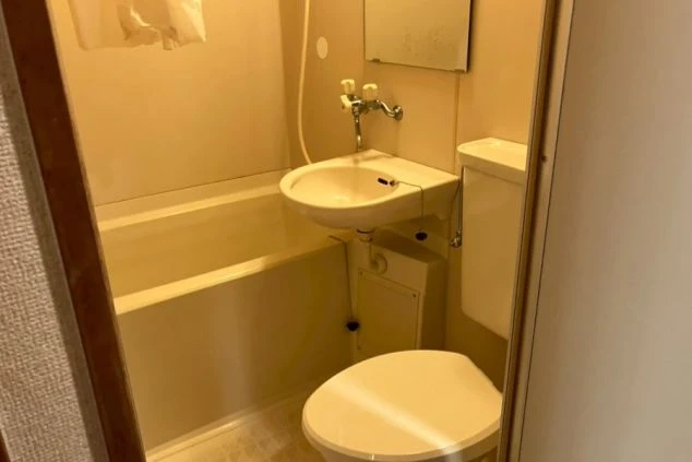 リゾートバイトの寮に備え付けられたユニットバスの画像。バスタブと便座、洗面台がまとまって配置されている。清潔感のある、寮の風呂場の画像。