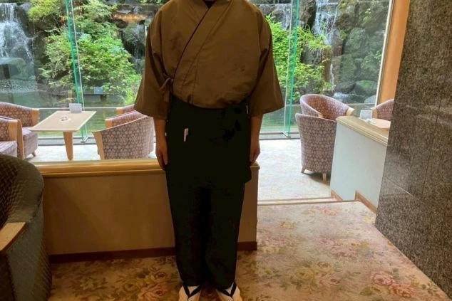 茶色い着物風の上着に黒い前掛けとズボン、そして草履(ぞうり)を着用した男性スタッフの画像。リゾートバイトの仕事内容を表す、レストランスタッフの制服の画像。