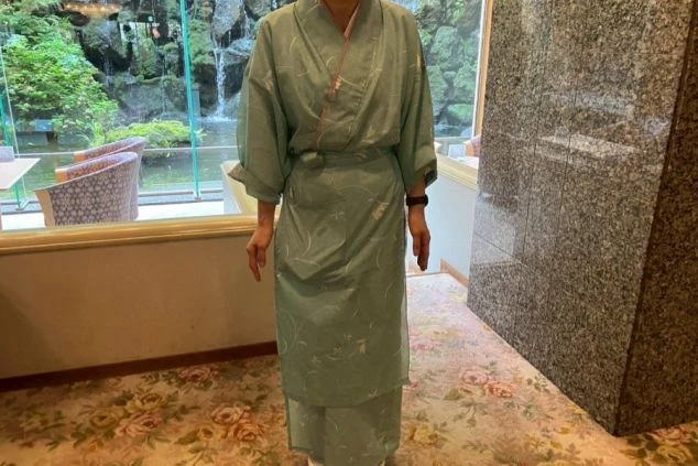 緑色の着物風の制服を着用した女性スタッフの画像。上下ともに淡い色合いで、花柄の模様が入っている。リゾートバイトの仕事内容を表す、レストランスタッフの制服の画像。