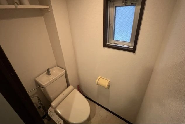 リゾートバイトの寮の個室トイレ。温水洗浄便座が設置され、上部には収納棚も備え付けられている。