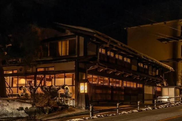 雪が積もる夜の旅館の外観。ライトアップされた幻想的な雰囲気の中で、リゾートバイトの生活を送れます。