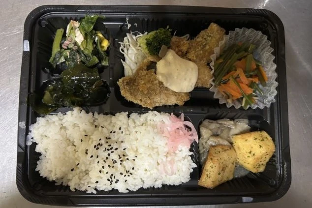 白身魚のフライ、きんぴらごぼう、煮物、サラダなど、様々な種類のおかずが詰まったお弁当。