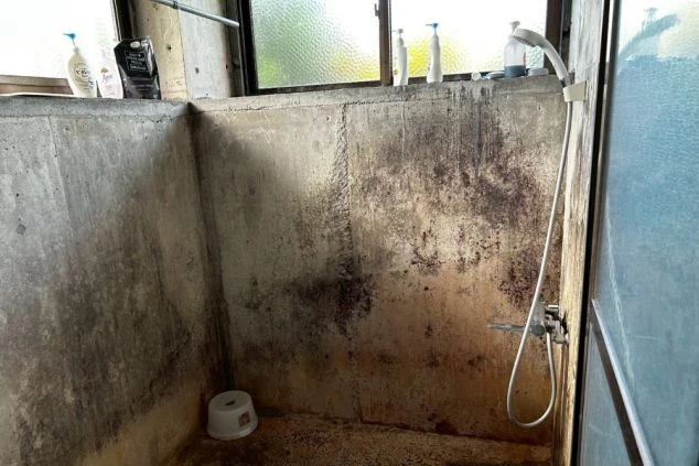 リゾートバイトの寮の共用シャワールーム。コンクリート打ちっぱなしの壁が特徴的な、シンプルなシャワー設備です。