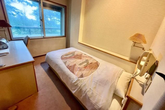 リゾートバイトの寮の個室。ベッド、机、椅子が備え付けられた、ホテルの客室のようなプライベート空間。