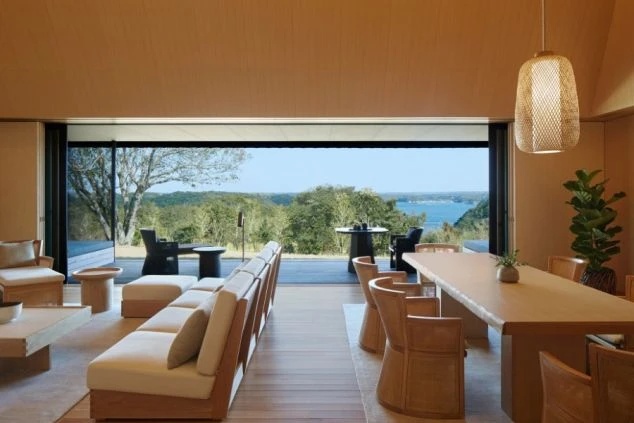 建物の正面。大きな瓦屋根と黒い壁のモダンな和風建築で、全面ガラス戸の向こうに室内が見える。手前は手入れされた芝生で、飛び石がある。