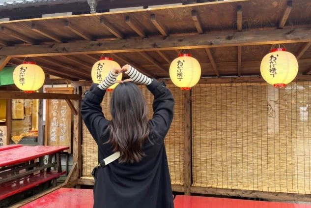 建物の正面。大きな瓦屋根と黒い壁のモダンな和風建築で、全面ガラス戸の向こうに室内が見える。手前は手入れされた芝生で、飛び石がある。