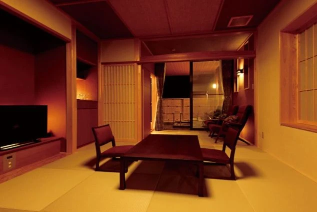 温泉旅館の客室。畳敷きの和室に、テレビや座卓が置かれている。障子戸の向こうにはベッドルームと露天風呂が見え、リゾートバイトの寮や客室の快適さをアピール。