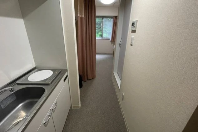 リゾートバイト先の寮の部屋にあるキッチンの画像。奥には寝室が見える。