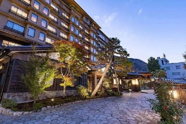 ライトアップされた和風の旅館の外観の画像。紅葉した木々が美しく、落ち着いた雰囲気が漂っている。リゾートバイトの仕事場となる、ホテルや旅館の外観の画像。