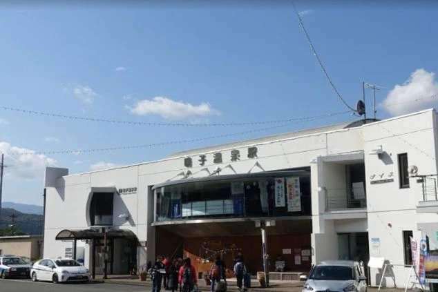 鳴子温泉駅の外観。白と木目調のモダンな駅舎に「鳴子温泉駅」の文字が見える。リゾートバイトの勤務地へのアクセスをアピール。