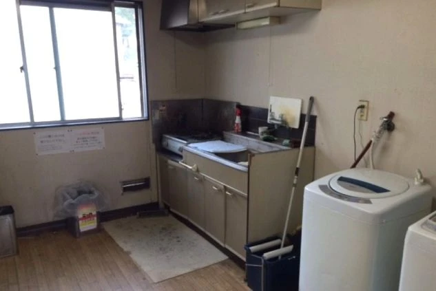 リゾートバイトの寮にある共用キッチン。コンロ、シンク、換気扇、そして洗濯機も備え付けられており、生活に必要な設備が揃っている
