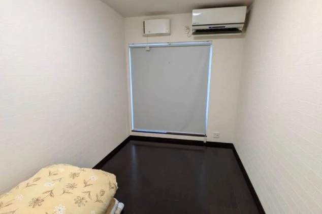 リゾートバイトの個室寮の部屋の画像。エアコンがあり白い壁の部屋の中に布団が用意されている。
