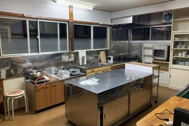 リゾートバイトの寮にある、広々とした共用キッチンの画像。ステンレス製の調理台や複数のコンロがあり、休日には仲間と料理を一緒に楽しむこともできます。