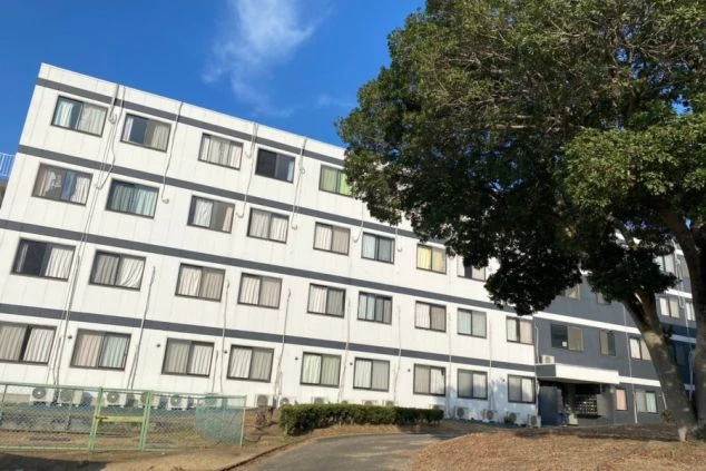 リゾートバイトの社員寮の外観を表現するイメージ画像。白とグレーを基調とした、4階建ての大きな建物。