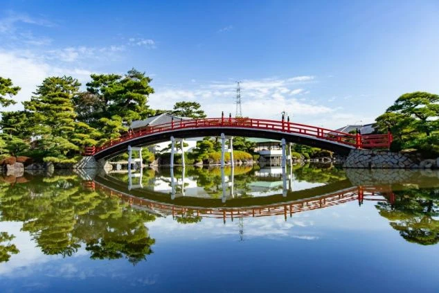 日本庭園の風景。赤い太鼓橋が池の水面に反射しており、美しい景色を創り出している。