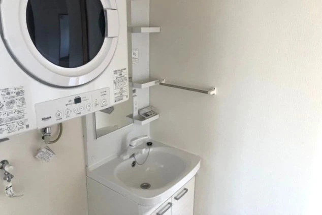 リゾートバイト寮の洗面台。洗面台の上にはドラム式洗濯乾燥機が設置されており、生活に便利な設備が整っている。