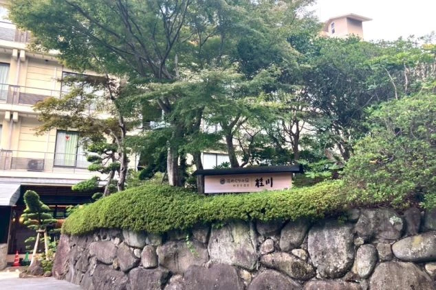 苔むした石垣と緑に囲まれた、落ち着いた雰囲気の温泉旅館「桂川」の外観。