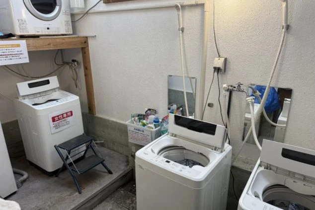 寮の共用ランドリースペース。複数台の洗濯機が設置され、洗剤なども用意されています。