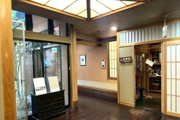 リゾートバイト勤務地の旅館の外観。色づく木の葉が印象的な日本庭園の奥に旅館の入口がある。