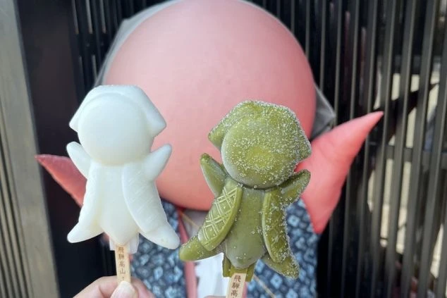 飛騨高山の観光地で、さるぼぼをかたどったアイスキャンディーを手に持っている画像。リゾートバイトの休日にご当地グルメを楽しんでいる様子が伝わってくる画像。