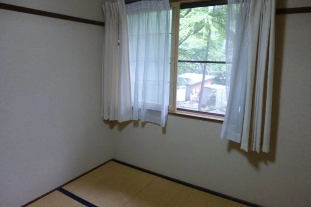 和室の寮の部屋の画像。畳敷きの空間に窓があり、外の景色が見える。シンプルな内装で、落ち着いて過ごせる居住空間。