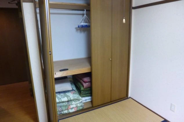 和室の寮の収納スペースの画像。布団や衣類を収納できる棚とハンガーポールが備え付けられている。リゾートバイト中の荷物の整理に便利。