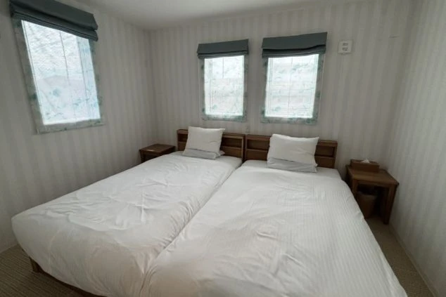 宮古島のリゾートバイトで利用できる、清潔なツインベッド完備の個室寮の画像。白を基調とした落ち着いた内装の寝室。