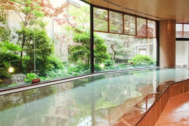 リゾートバイト先の温泉旅館の温泉浴場。ガラス張りの窓から美しい庭園を眺めながら入浴できる。リゾートバイトの特典として仕事終わりに利用できる温泉。