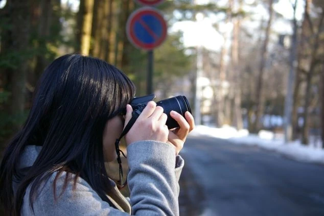 軽井沢の冬景色をカメラで撮影する女性の画像。リゾートバイトのオフに趣味を楽しむ様子。