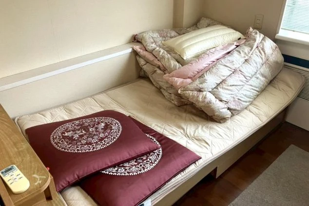 ベッド、机、椅子が備え付けられたリゾートバイト寮の個室の画像。