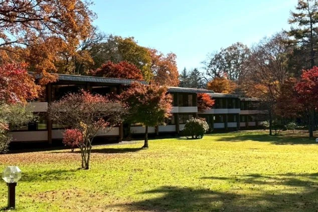 紅葉に囲まれた広々とした庭園と、落ち着いた雰囲気のホテルの外観。