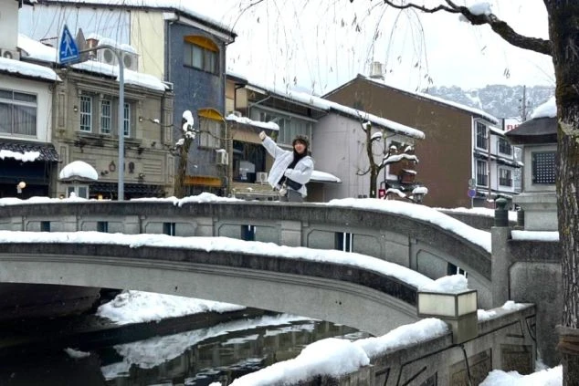 兵庫県・城崎温泉の雪景色でポーズをとる女性の画像。リゾートバイトのオフの観光。