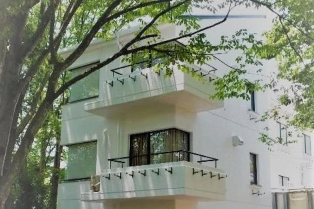 リゾートバイトの寮の外観。緑豊かな木々に囲まれた、バルコニー付きの白い清潔感のある建物です。