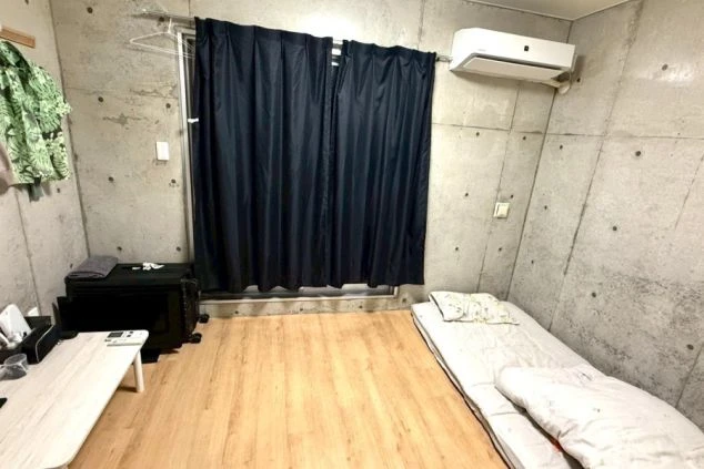 石垣島リゾートバイトの個室寮。打ち放しコンクリートがおしゃれな室内で、布団やエアコン完備の快適な住み込み環境。