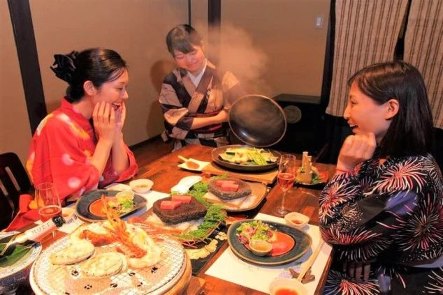 浴衣姿で豪華な食事を楽しむお客様と、おもてなしをするスタッフ。旅館での接客に興味がある方へ。