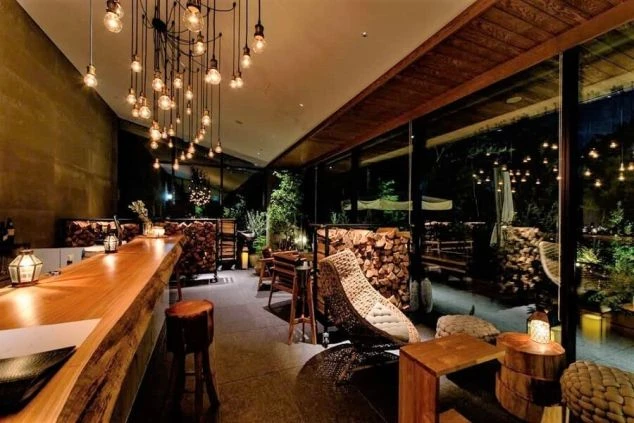 木やレンガを基調としたシックな雰囲気のレストランの画像。ガラス張りの炉端焼きスペースで、炎が上がり調理している様子が見える。リゾートバイトの仕事内容を表す、ホテルのダイニングの画像。